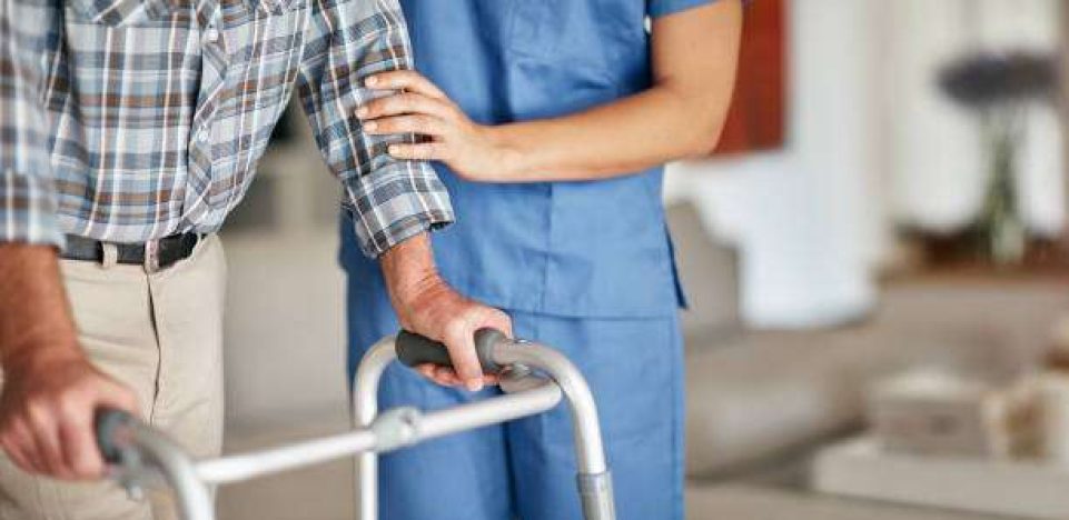 Shot of a woman assisting her elderly patient who’s using a walker for support Shot of a woman assisting her elderly patient who's using a walker for support